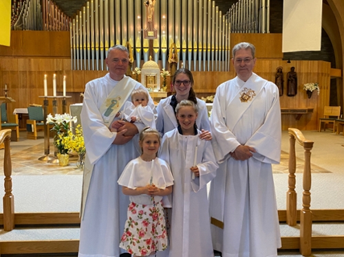 picture of a child, family, and clergy after a baptism